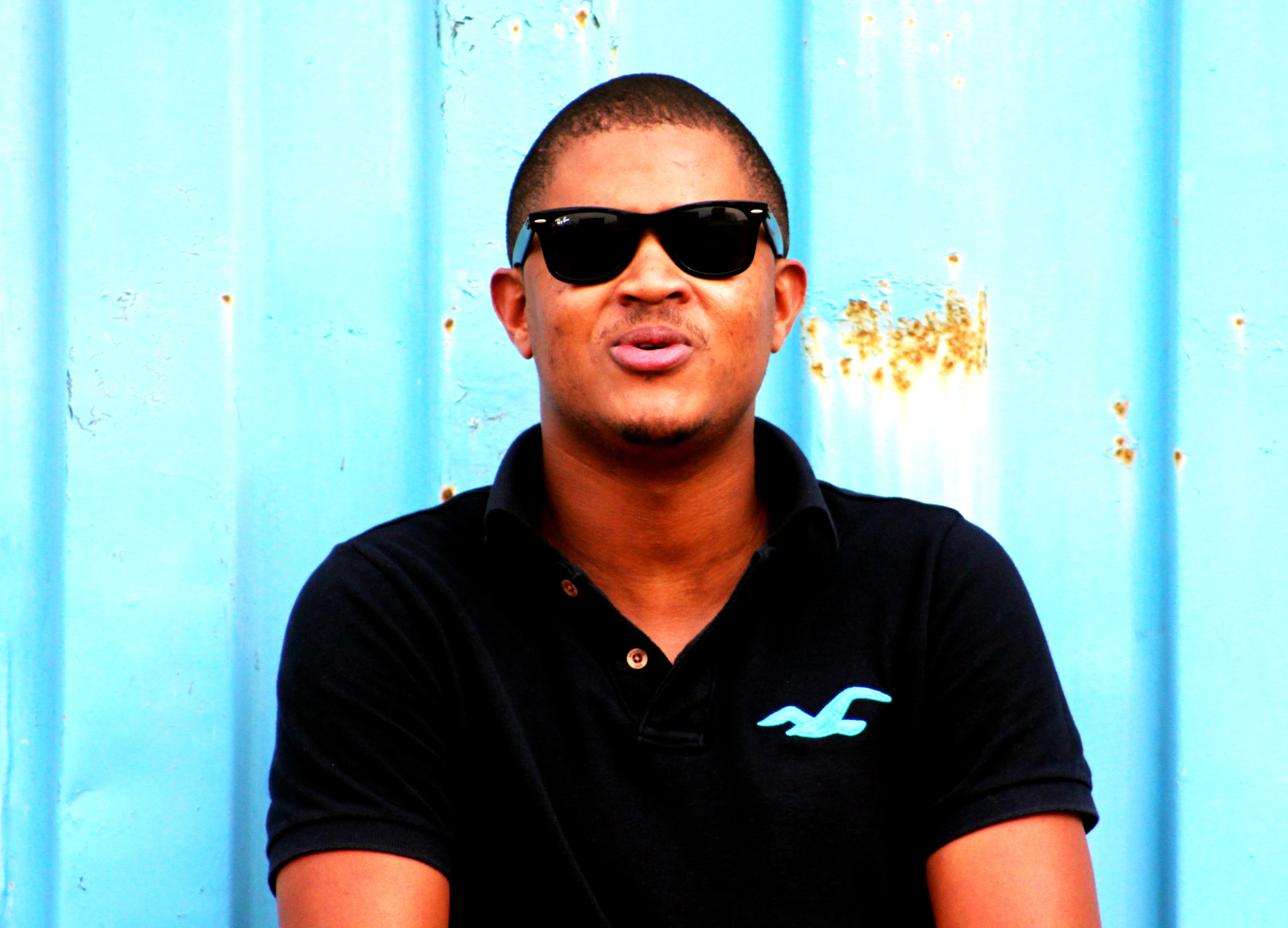Portrait of a man in sunglasses against a blue wall