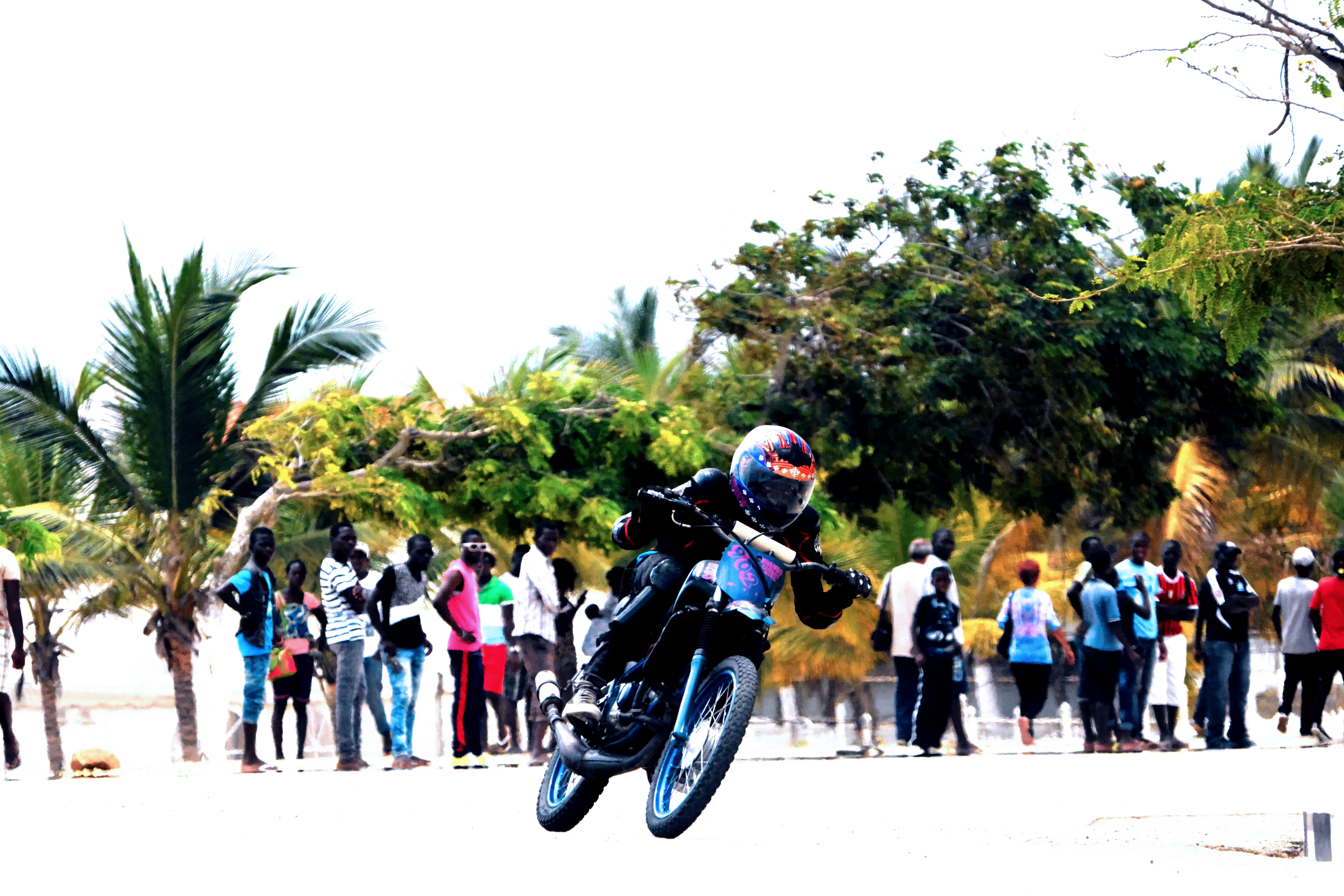 Motorcycle wheelie on the Luanda waterfront, crowd watching