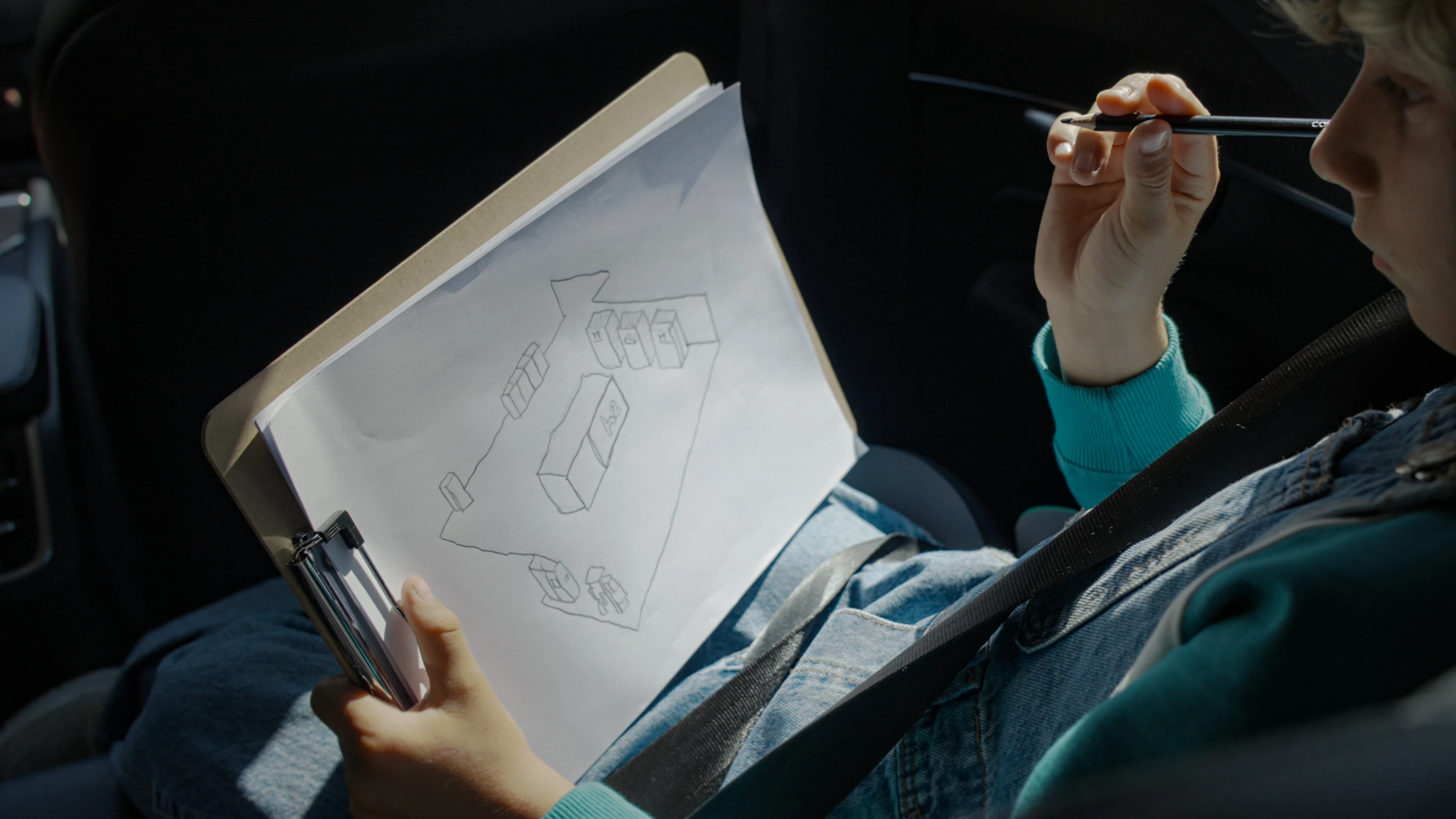 Child drawing the hydrogen station on sketchpad in backseat